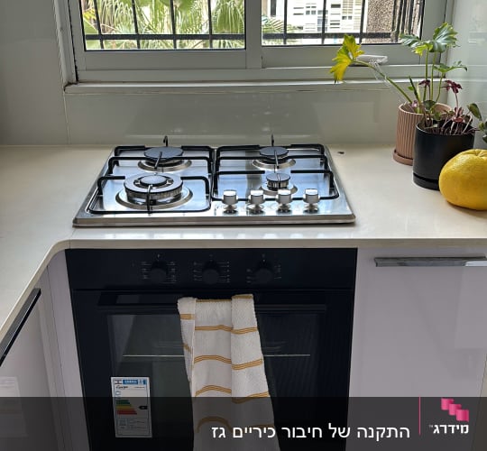כיריים גז עם ארבעה מבערים ומגבת תלויה על התנור
